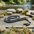 Black  shaligrambeaded necklace on a wooden surface with a natural background