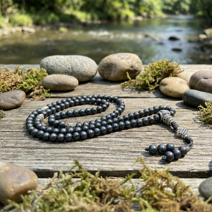 Black  shaligrambeaded necklace on a wooden surface with a natural background