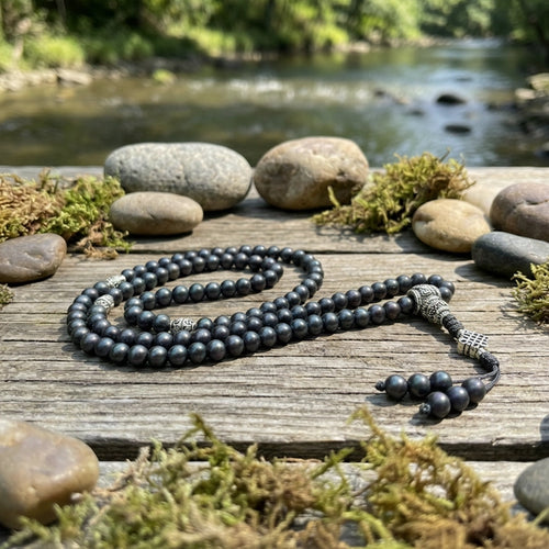 Black  shaligrambeaded necklace on a wooden surface with a natural background