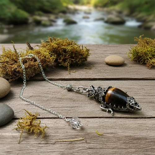 Dowsing pendant tigers eye ependant on a wooden surface with a natural background